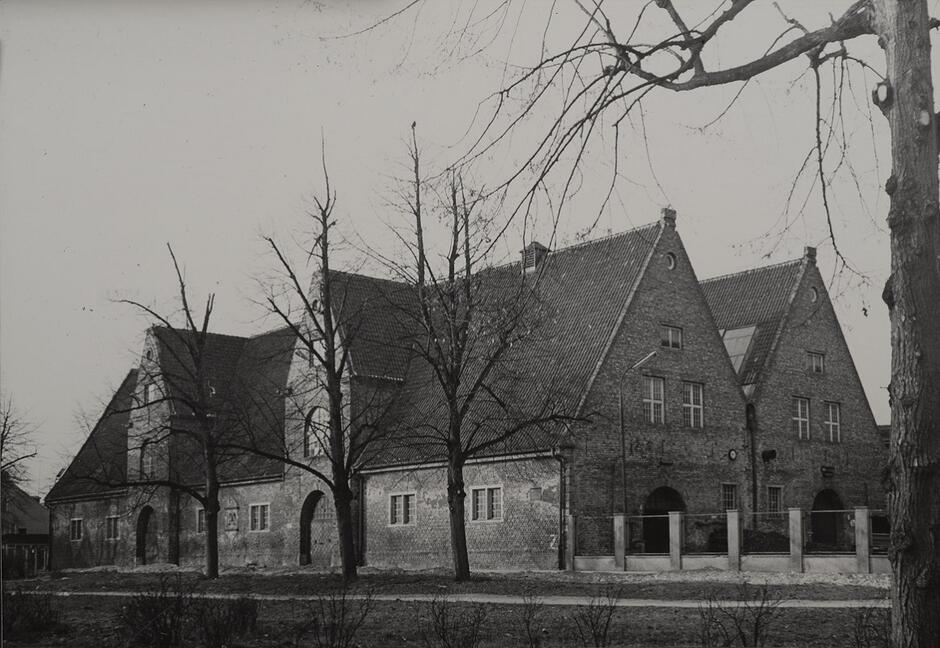 Budynek ceglany ze spadzistym dachu na czarno-białej fotografii