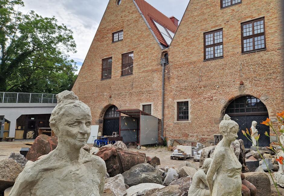 Rzeźby przedstawiające ludzi, stojące na podwórku przed budynkiem