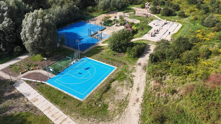 zdjęcie z drona, widać teren z trzema boiskami o niebieskiej nawierzchni, oraz inne urządzenia do zabawy dla dzieci