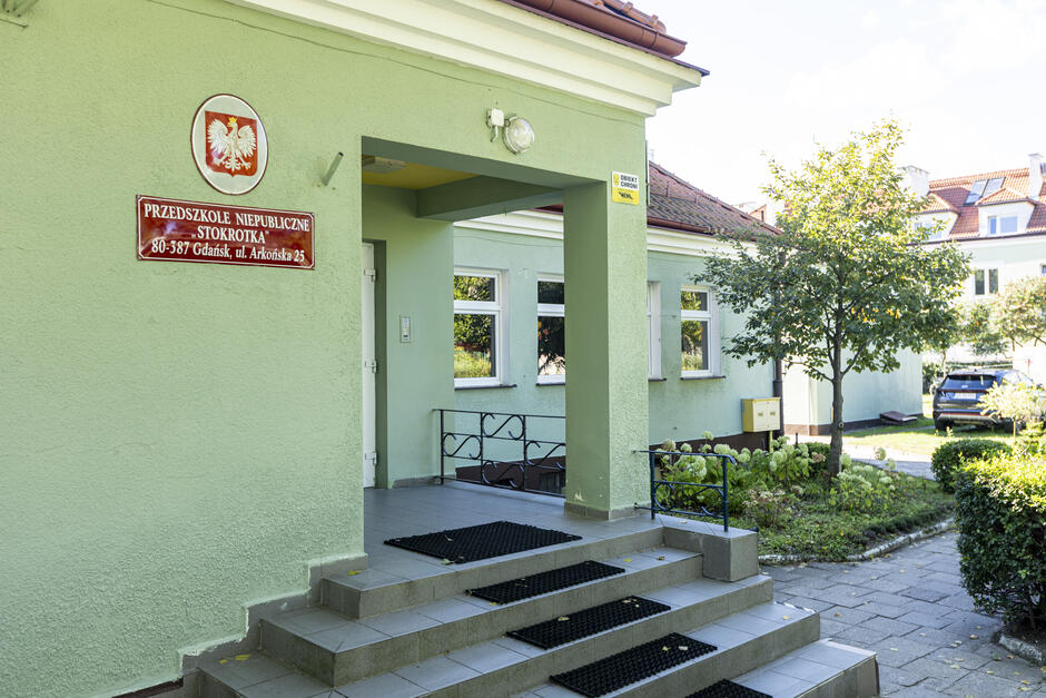 wejście do parterowego budynku otoczonego zielenią