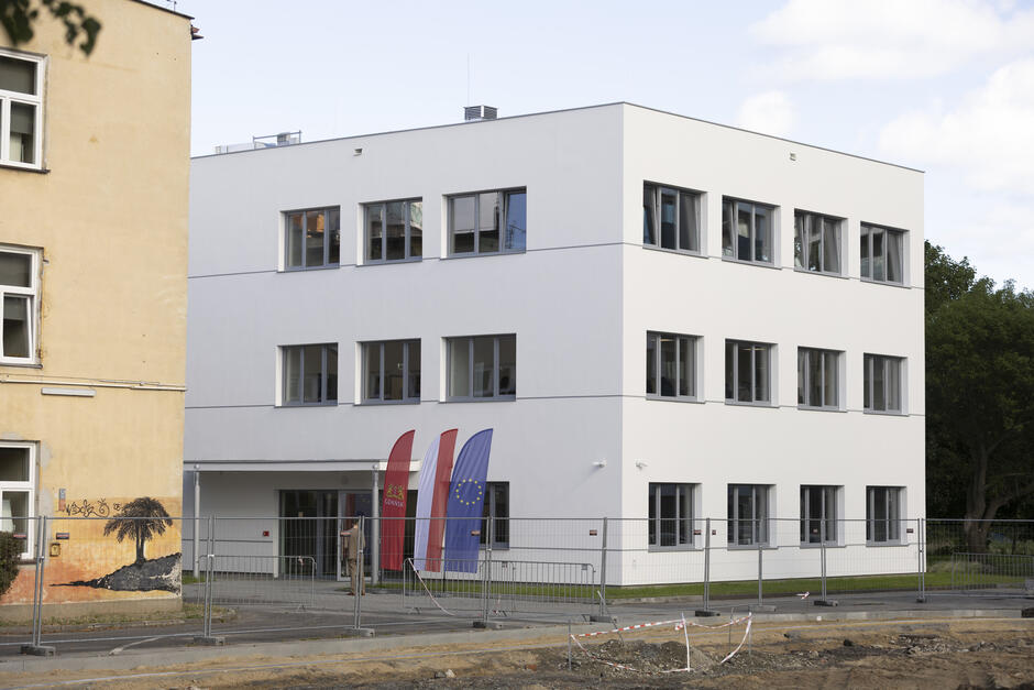 Nowo wybudowany dwupiętrowy budynek obok starego budynku szkoły.