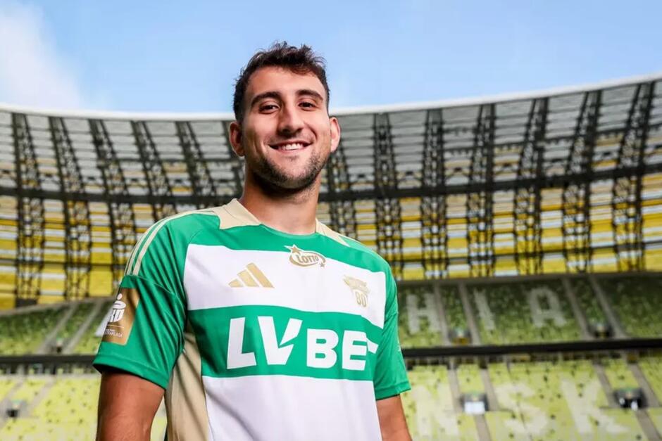 Młody uśmiechnięty zawodnik w biało-zielonym stroju