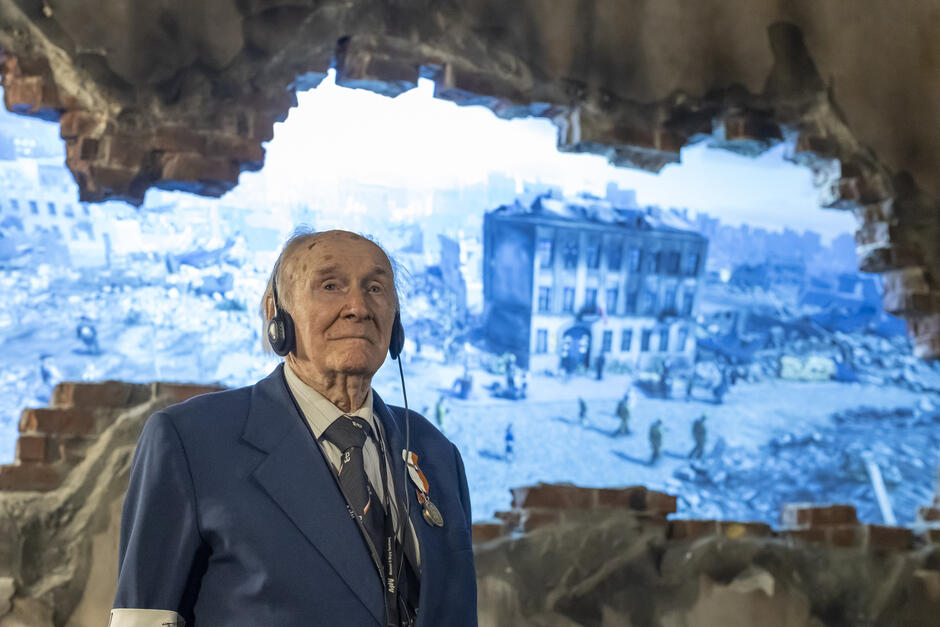 Mężczyzna w podeszłym wieku ze słuchawkami na uszach w muzeum.