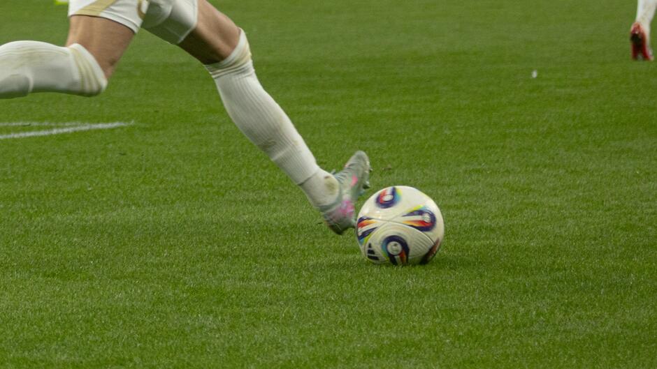 Noga piłkarza, która uderza piłkę na murawie boiska
