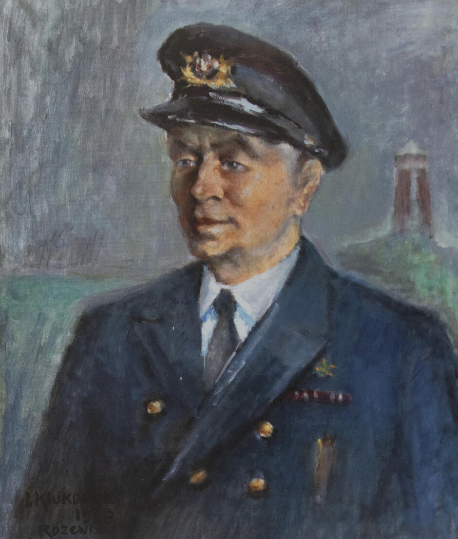 Obraz przedstawia mężczyznę w granatowym mundurze marynarskim i czapce z emblematem, namalowanego na tle wizerunku latarni morskiej. Artysta oddał realistyczne rysy twarzy i wyraz spokoju portretowanego, podkreślając jego związek z morzem. 