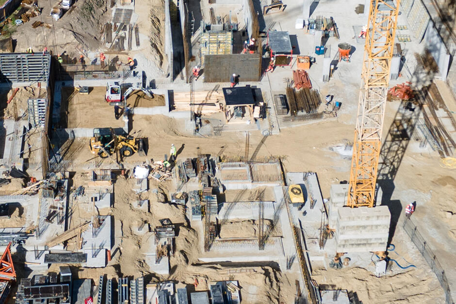 zdjęcie z drona, widać plac budowy z bliska, w tym betonowe elementy przyszłego budynku