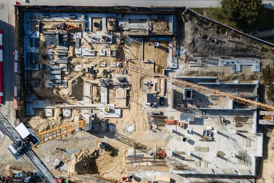 zdjęcie z drona, widać plac budowy, w tym betonowe elementy nowego budynku