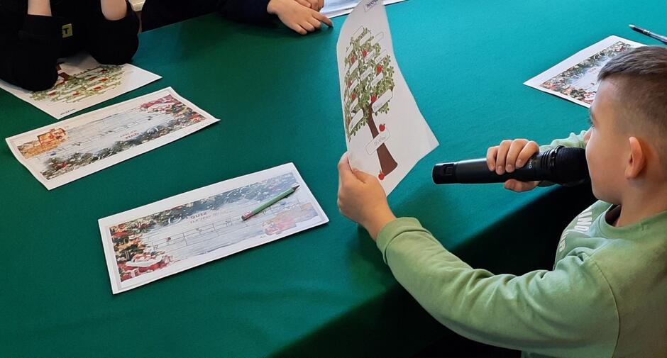 dziecko siedzi przy stole i pracuje nad drzewem genealogicznym.