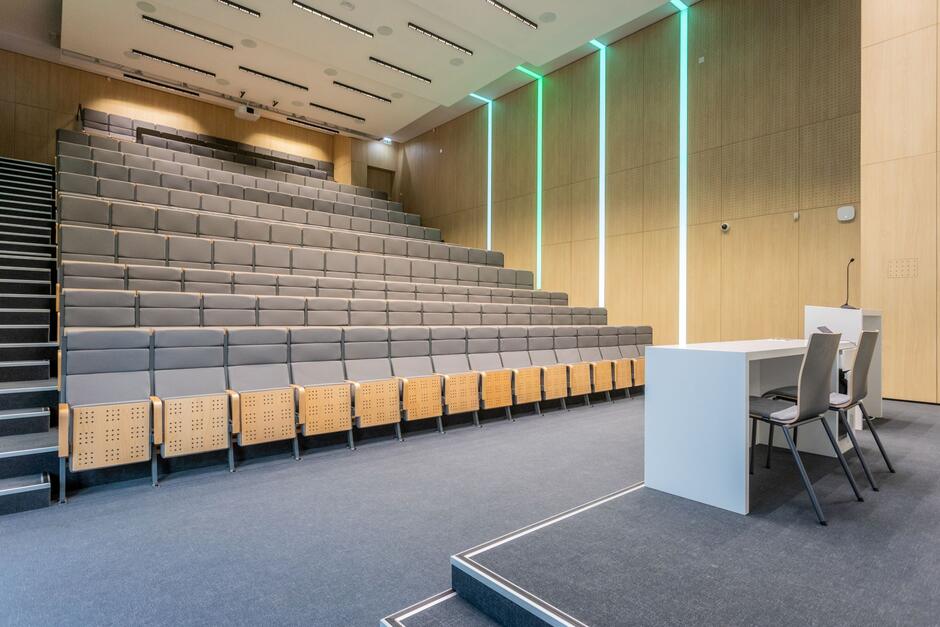 Sala dydaktyczna ze wznoszącymi się rzędami krzeseł.