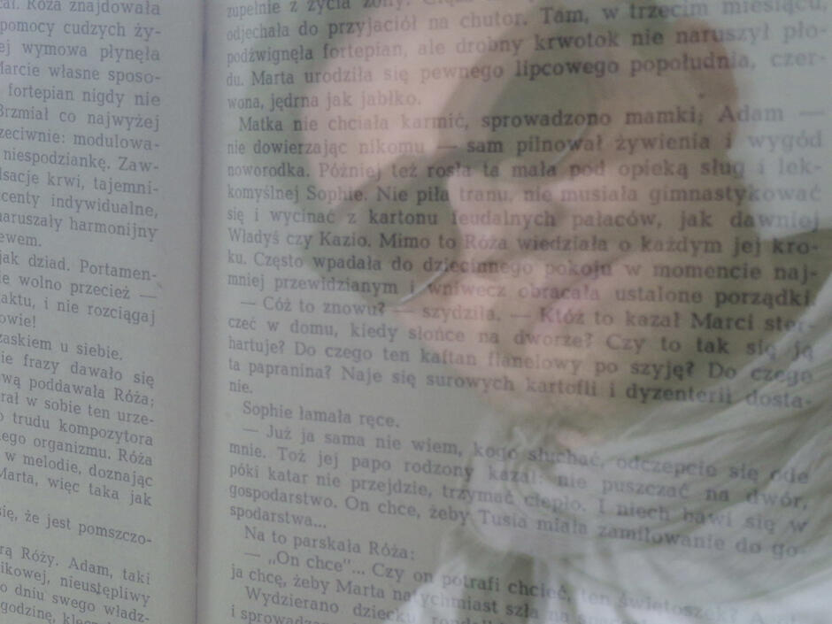 Na zdjęciu mężczyzna w okularach przeciwsłonecznych, na tle rozmytego tekstu książki. 