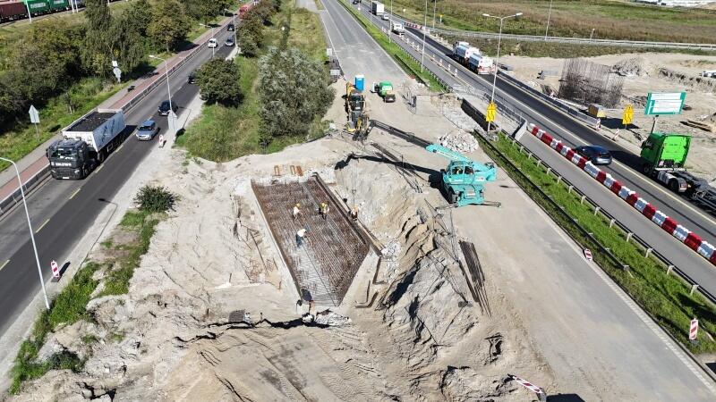 na zdjęciu zbrojenie metalowe przyszłego filaru wiaduktu, widać plac budowy i zielony dźwig po prawej