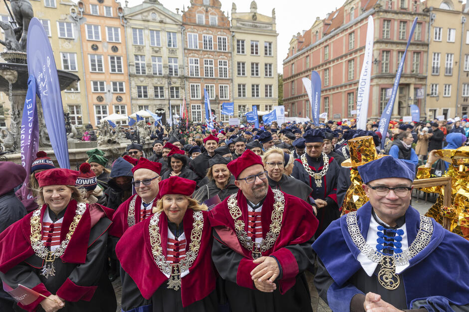 na zdjęciu naukowcy, wykładowcy akademiccy w togach i biretach, widać tłum ludzi, w tle kamienice gdańskie