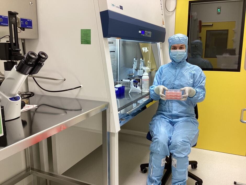 Pracownik w uniformie zabezpieczającym trzymający w ręce próbówkę