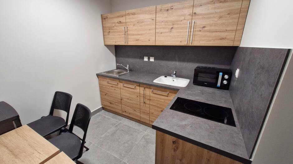 pomieszczenie kuchni z szafkami, zlewem, umywalką i kuchenką mikrofalową