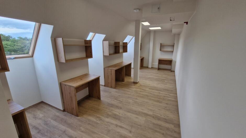 Wnętrze pod dachem ze skosami. Dachowe okna i biurka w sali