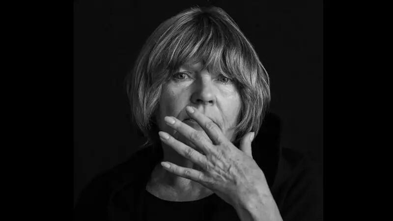 Czarno-białe zdjęcie. Kobieta w średnim wieku trzymająca dłoń na wysokości ust.