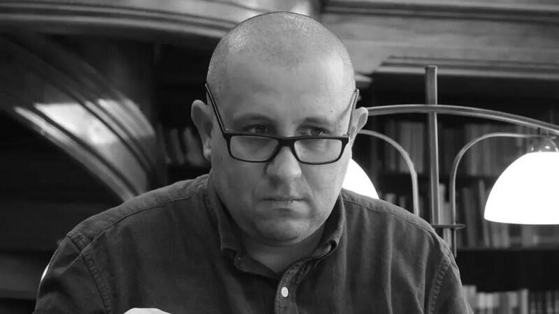 Czarno-białe zdjęcie. Twarz łysego mężczyzny w okularach w średnim wieku