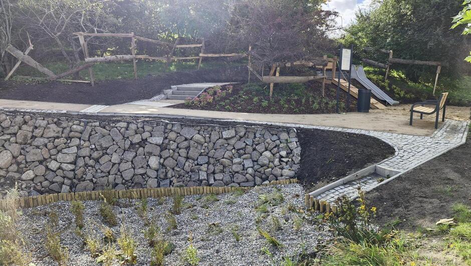 na zdjęciu uporządkowany teren parkowy, z widoczną kamienną ścianką