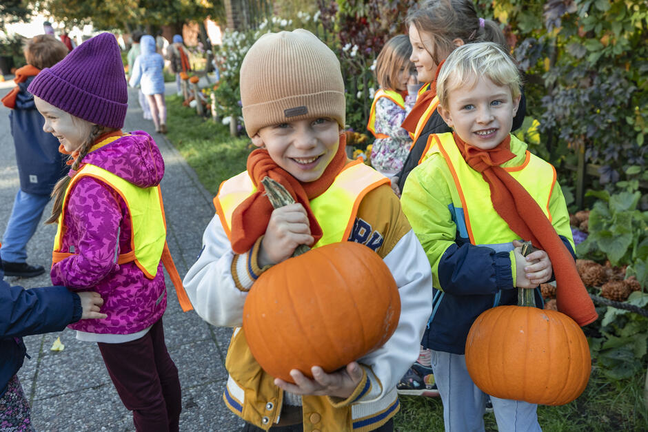Dwoje dzieci, które w rękach trzymają dynie