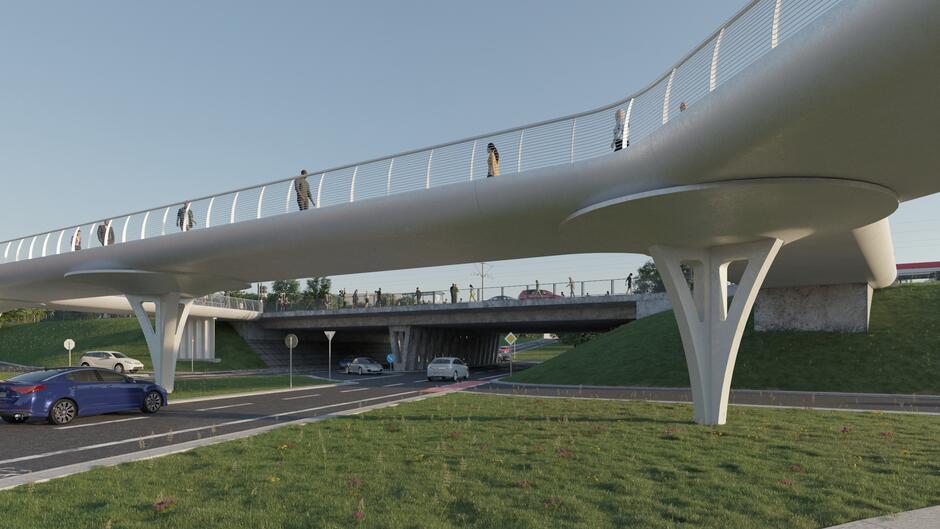 Wizualizacja przedstawia nowoczesną kładkę pieszo–rowerową o opływowych kształtach, wspartą na eleganckich filarach. Pod konstrukcją przebiega ruchliwa ulica, a całość otoczona jest zielenią i nową infrastrukturą miejską. 