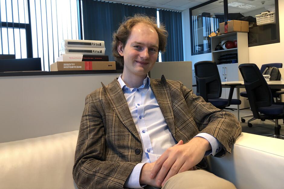 Młody człowiek - siedzi i uśmiecha się 