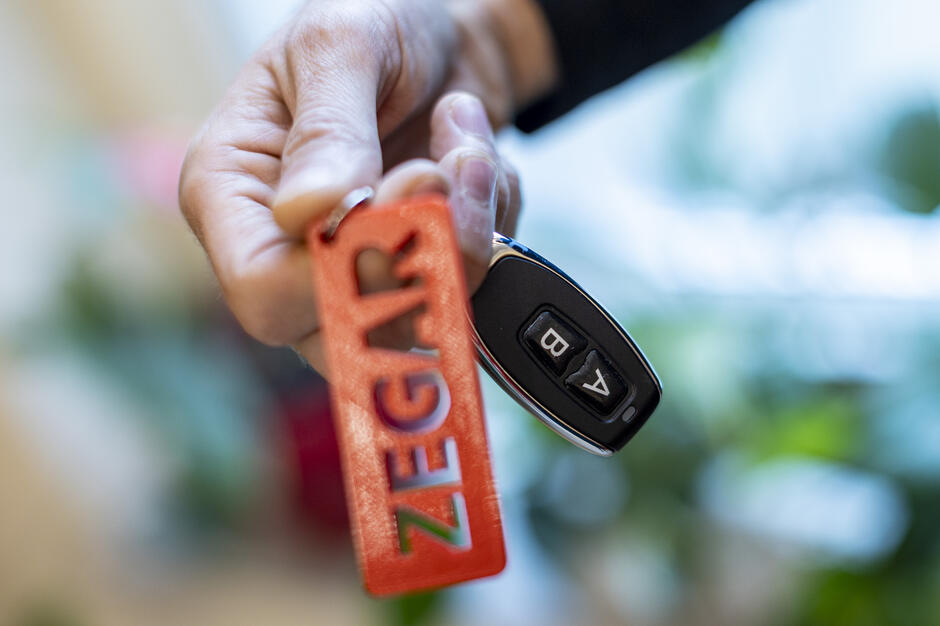 Na pierwszym planie ktoś trzyma pilot z przyciskami „A” i „B”.