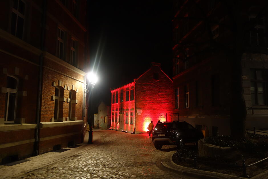 Podświetlona na czerwono ceglana kamienica w nocnej scenerii