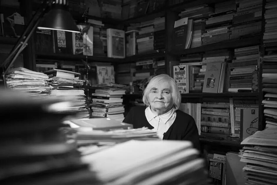 Siwa Maria Janion siedzi wśród stosów książek