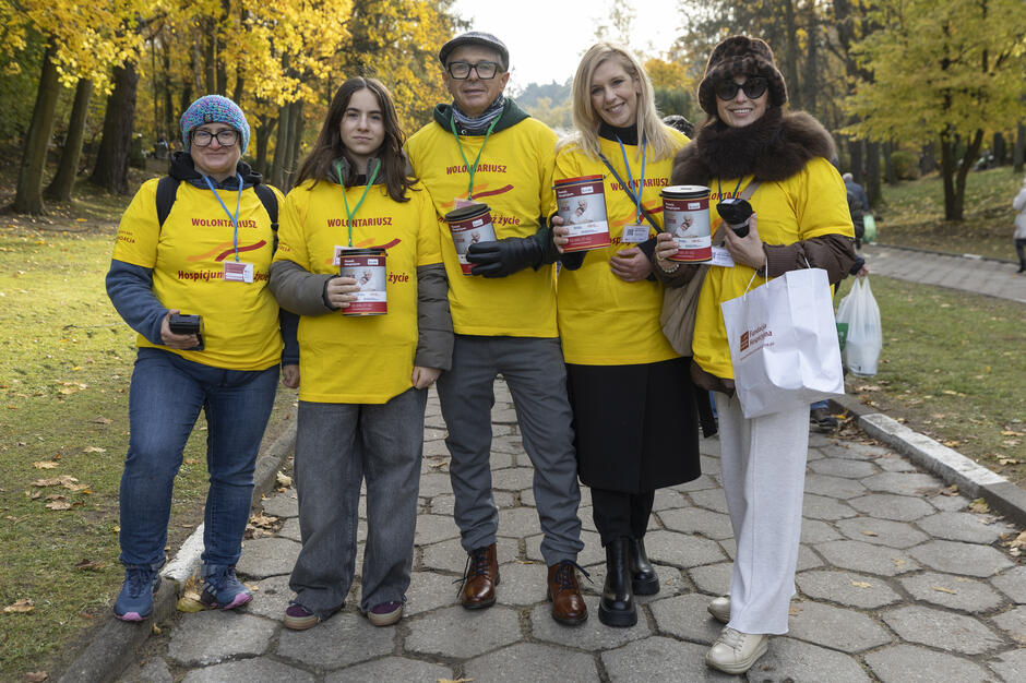 Pięć osób wspólnie pozuje do zdjęcia, są z puszkami, w żółtych koszulkach