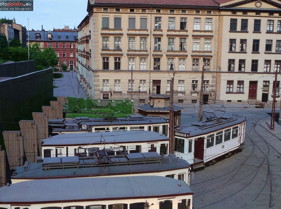 Białe tramwaje przy wjeździe do zajezdni, z tyłu wysokie kamienice
