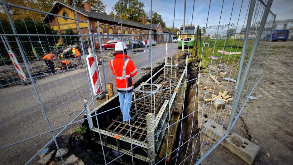 na zdjęciu kobieta w robotniczym stroju, obok niej fragmenty budowanych fundamentów