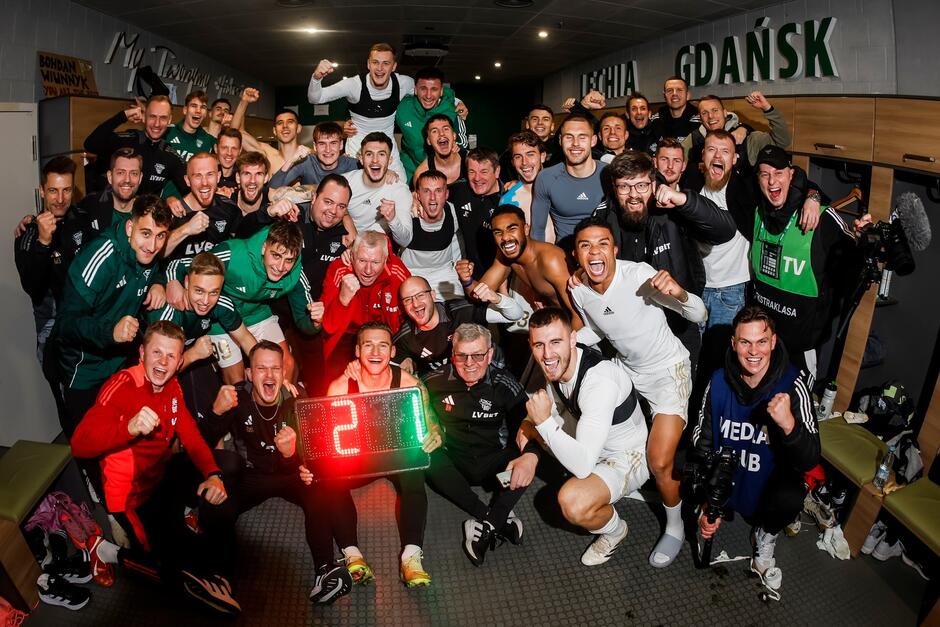 Grupowe zdjęcie około 30 osób z entuzjazmem pozujących do wspólnego zdjęcia