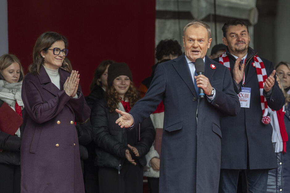 Grupa osób na scenie. Premier Tusk pośrodku, Aleksandra Dulkiewicz po lewej, Lech Parell po prawej 