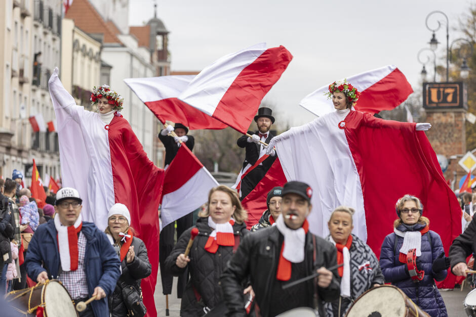 Grupa osób z biało-czerwonymi ubiorami i flagami na ulicy Gdańska