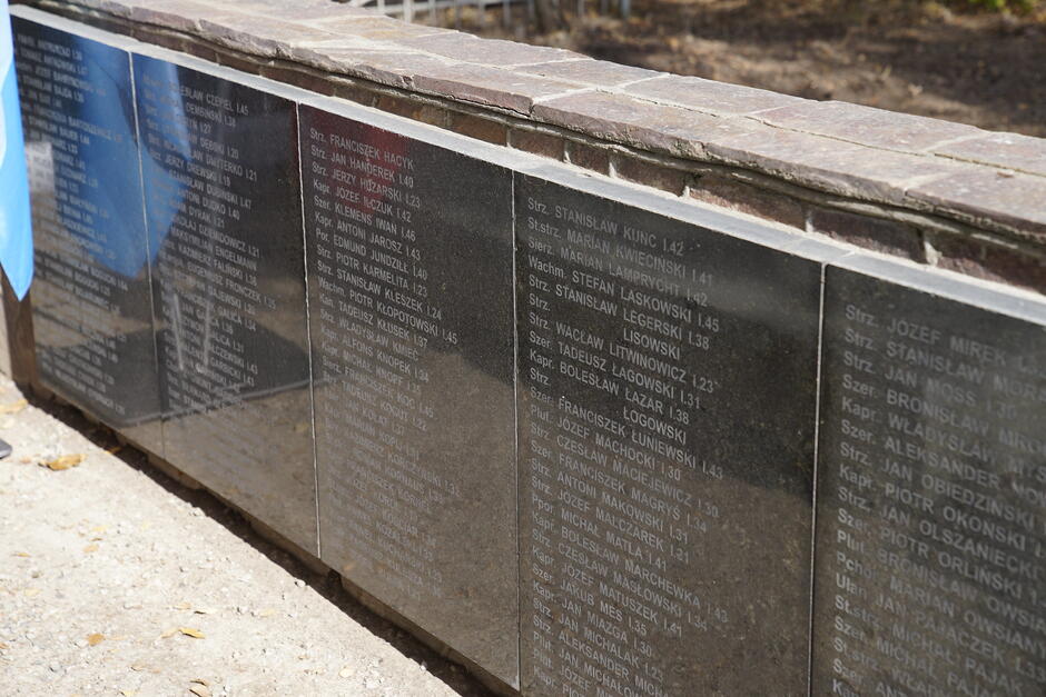 Czarna marmurowa tablica osadzona pionowo w ścianie