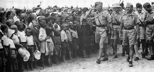 Po lewej dzieci w dużej grupie - po prawej generał idzie ze sztabem jakby na defiladzie