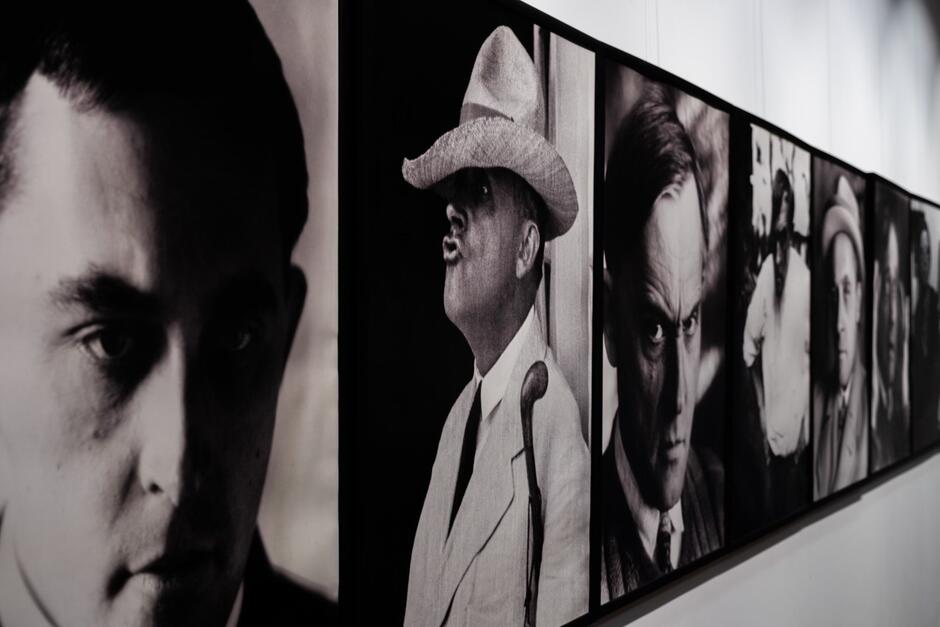 Na ścianie galerii zawieszono czarno-białe portrety mężczyzn o zróżnicowanych wyrazach twarzy, utrwalonych w dynamicznych, pełnych emocji ujęciach. Fotografie tworzą spójną sekwencję ukazującą indywidualne charaktery i nastroje epoki.
