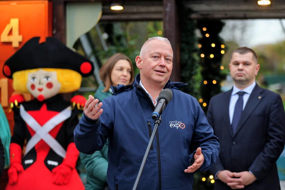 na zdjęciu mężczyzna w średnim wieku, mówi do mikrofonów, wyraźnie gestykulując