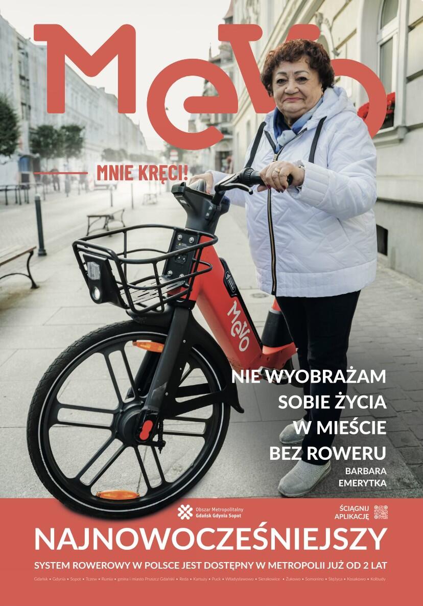 Na plakacie widać starszą kobietę stojącą obok czerwonego roweru miejskiego Mevo na tle miejskiej ulicy z ławkami i kamienicami. Grafika promuje korzystanie z systemu rowerów publicznych w metropolii, podkreślając jego znaczenie dla codziennego życia mieszkańców. 