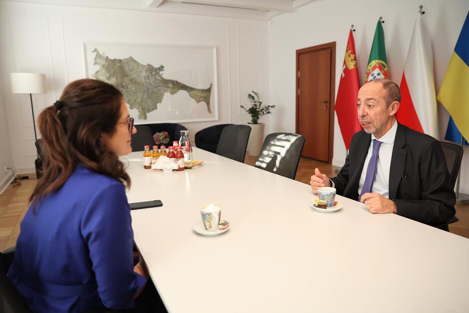 Dwie osoby rozmawiają przy stole. obieta po lewej, mężczyzna - po prawej