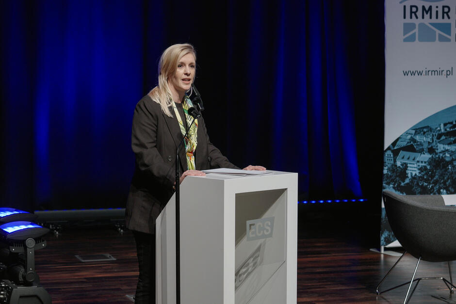 Kobieta stoi na mównicy i przemawia.