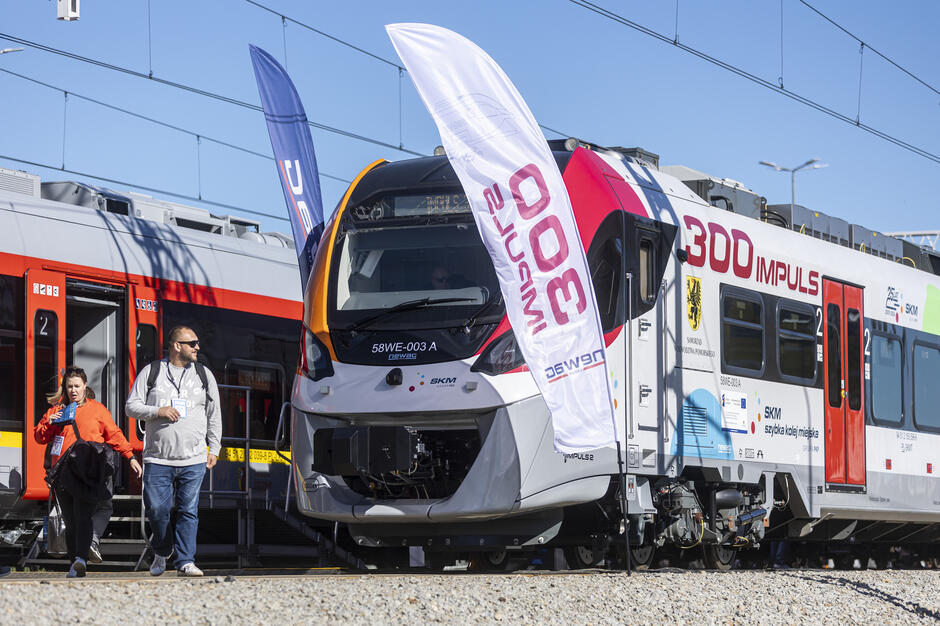 pociąg stoi na torach, na boku numer 300, stoi przy nim flaga z napisem 300