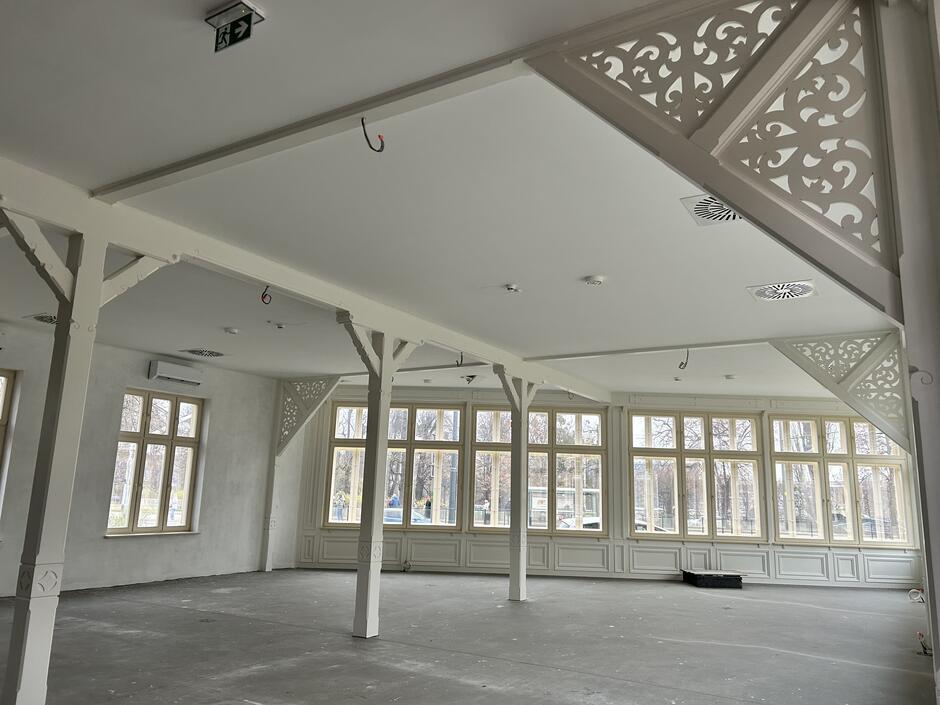 wnętrze budynku, jasna sala, bardzo przestrzenna z drewnianymi elementami ozdobnymi, także jasnymi