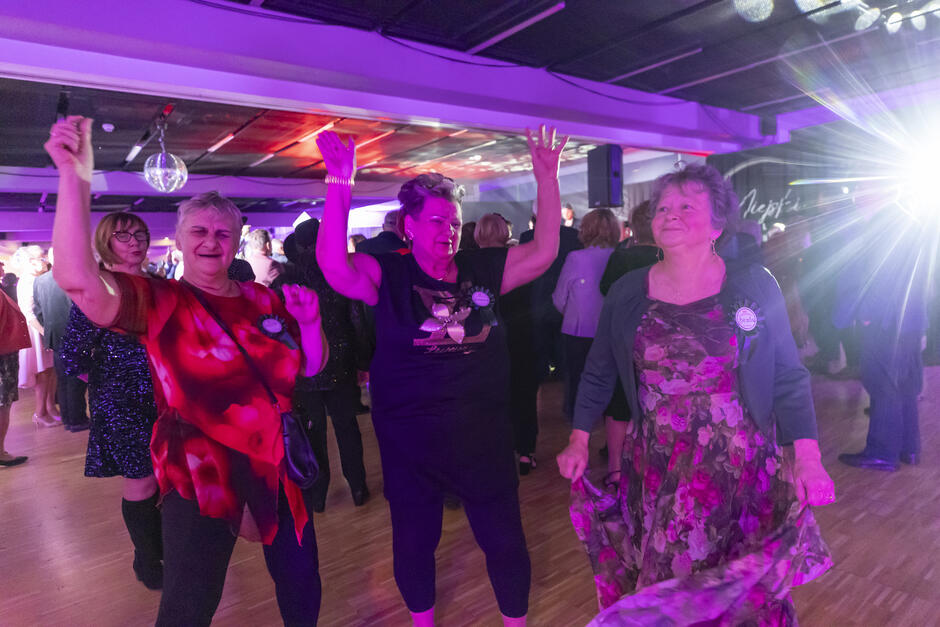 na zdjęciu trzy starsze tańczące na parkiecie panie