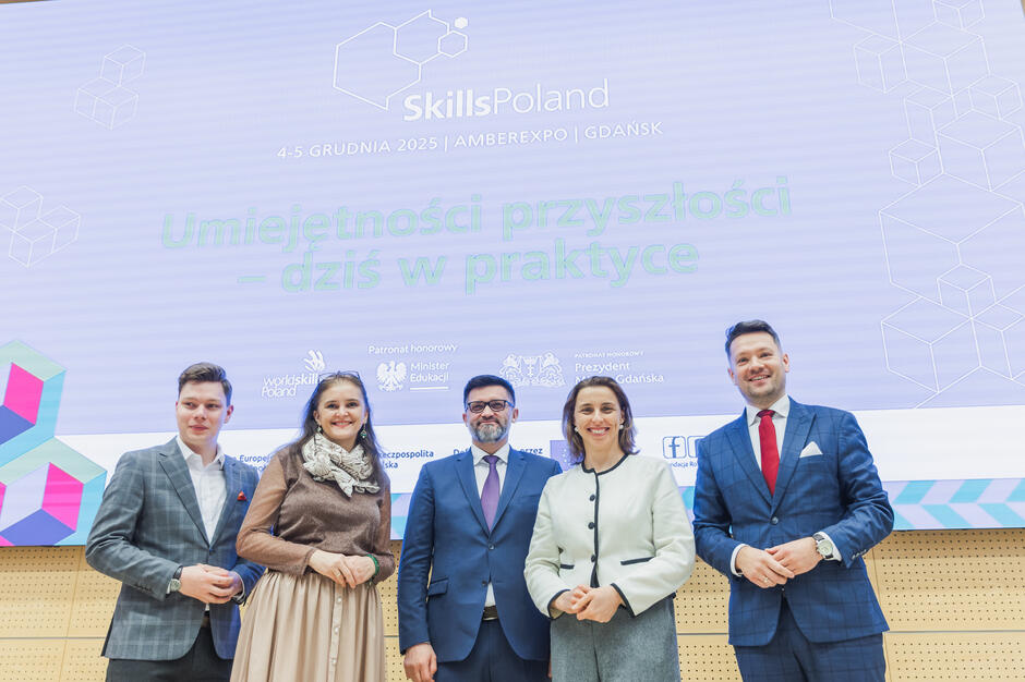 do zdjęcia pozuje pięć osób, dwie kobiety i trzech mężczyzn, wszyscy elegancko ubrani