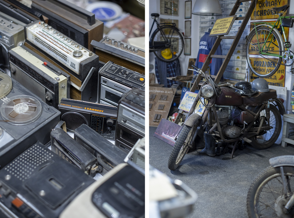 Stół i walizki wypełnione są różnymi przedmiotami z minionych dekad, takimi jak dokumenty, pieczątki, banknoty, odznaczenia i drobne narzędzia. W pomieszczeniu wisi portret radzieckiego przywódcy w mundurze, otoczony kolekcją medali i pamiątek historycznych.
