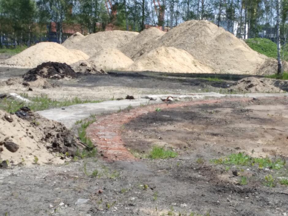 Fragment odkopanego okrągłego fundamentu z cegieł, a w tle hałdy piasku