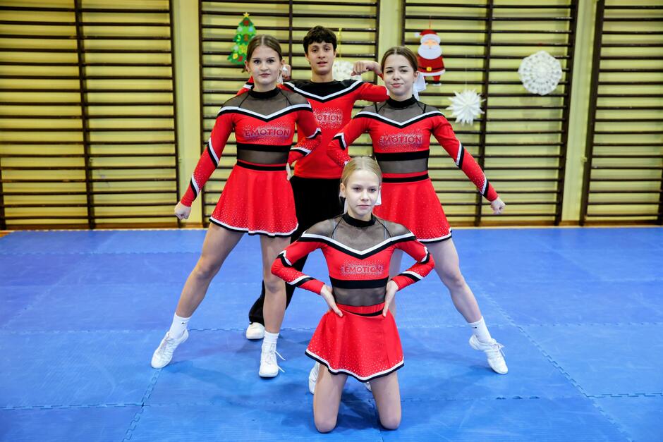 na zdjęciu pozują trzy uczennice i jeden uczeń w strojach sportowych, gimnastycznych