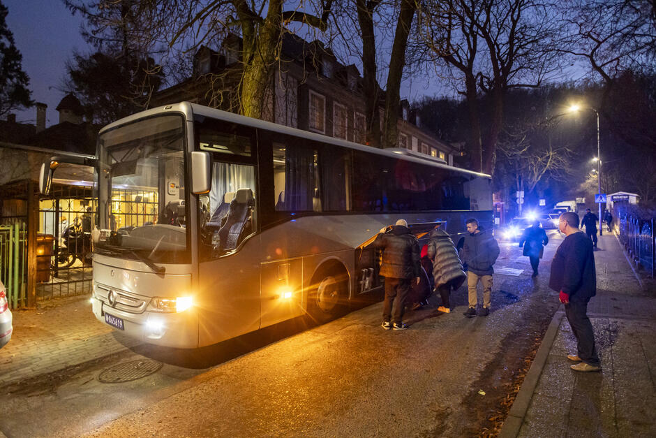 Autokar zaparkowany w wąskiej ulicy - pakują rzeczy do luku bagażowego