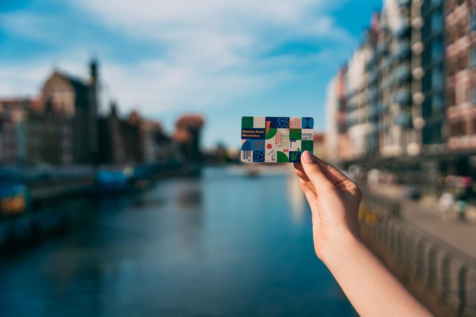 na zdjęciu ludzka ręka trzyma plastikową kartę, przypominającą bankomatową